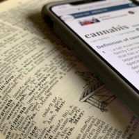 Silver iphone displaying cannabis definition on top of dictionary